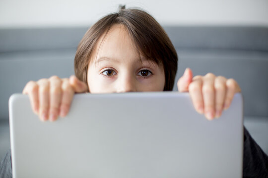 Preteen child, hiding behind notebook, online education, games and fun for kid, bad influence