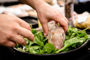 chef preparing food whole fish on bed of spinach