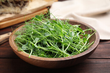 Plate with fresh microgreen on brown wooden table, closeup