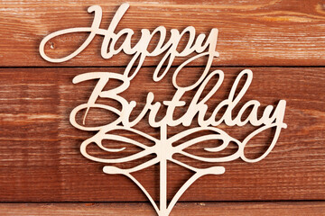 a wooden Happy Birthday lettering on brown wooden background