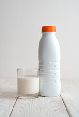 A milk bottle filled with a glass of milk on a gray background. Side view with copy space. The concept of dairy products.