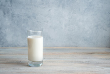 Milk in a long transparent glass on a gray-blue background. Side view with copy space. The concept of dairy products.