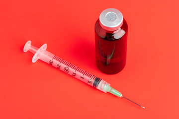 Disposable Syringe Injection And Amber Color Vial On Red Background
