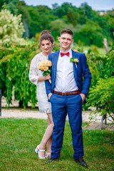 Fototapeta premium Groom in a bright blue suit and red bow tie on a walk in a summer park
