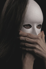 portrait of a woman in a white mask in the dark