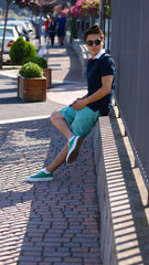 Pretty boy sitting on the street. Summer style in the streets of Italy