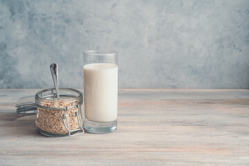 Milk with oatmeal on a light gray background. Vintage culinary background with toning and adding noise. Side view with copy space.