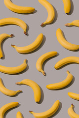 Creative pattern made with yellow bananas on a gray background. Minimal aesthetic concept.