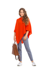 Full length portrait of beautiful stylish girl in fashion blue jeans and poncho with long curly hair posing - isolated on white background. Fashion model posing at studio. leather backpack in hand