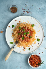 Pasta with thick sauce on a gray background. Top view, vertical orientation. The concept of a culinary background.