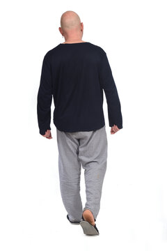 rear view of a man in pajamas walking on white background,