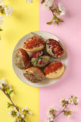 Easter concept with eggs decorated with different spices and cereals without dyes and preservatives on pink and yellow background. Vertical format