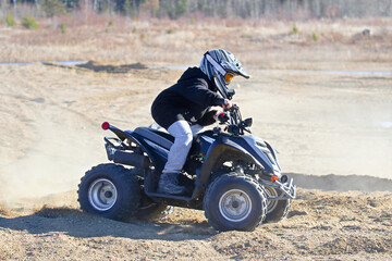 A young boy on his atv with a dusty background
