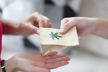 Handing over paper bag with marijuana sign. Marijuana delivery service concept