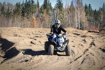 A young boy on a quad with tracks in gravel all around him