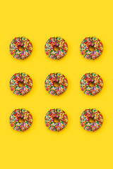 series of sprinkle donuts on yellow background