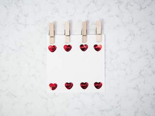 Fototapeta na wymiar Note paper with wooden clothespin and heart shape objects on marble background, happy valentine's day, mother's day, flat lay, top view