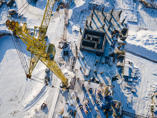 Concrete residential building in the process of construction with crane. Aerial view to the construction works on the top of concrete building.