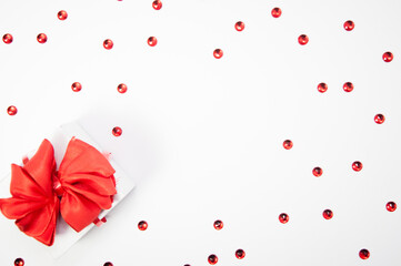 Creative composition made of red crystals and white gift box with red ribbon on white background with copy space, happy valentine's day, mother's day, flat lay, top view