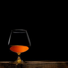 a glass of whisky with wooden box on black background
