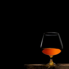 a glass of whisky with wooden box on black background