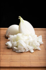 Fresh diced white onion on bamboo cutting board. Allium cepa. Black background