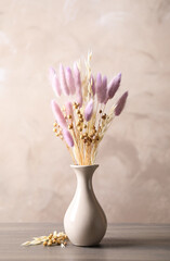 Dried flowers in vase on table against light grey background © New Africa