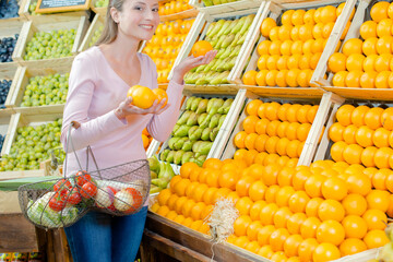 a woman is choosing oranges