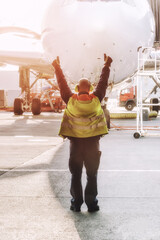 Ground Crew in the signal vest. Aviation Marshall. Aviation Supervisor meets passenger airplane at the airport. Aircraft is taxiing to the parking place.