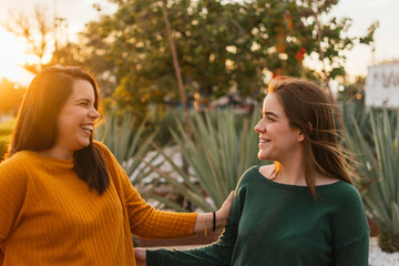 TWO WHITE WOMEN LAUGHING WITH THE SUNSET IN THE BACKGROUND