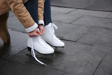 Woman lacing figure skate outdoors, closeup. Space for text