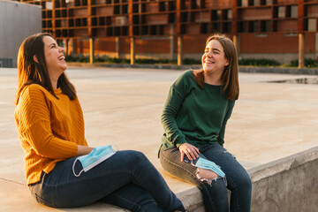 TWO WHITE WOMEN LAUGHING WITH THE FACE MASK IN HAND