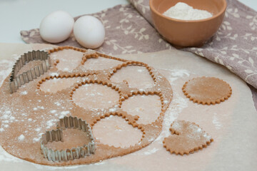 Cutting out heart-shaped cookies from raw dough using cookie cutters.