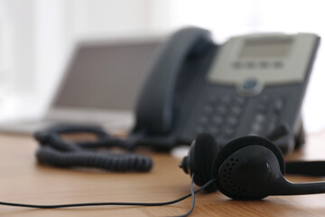 Headset on wooden table indoors, closeup with space for text. Hotline service