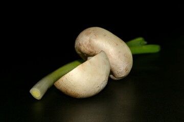 Mushrooms and green onion on black background