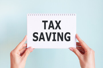 TAX SAVING word inscription on white card paper sheet in hands of a woman. Business concept