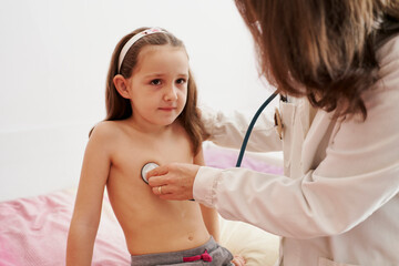 Pediatric doctor examine little happy girl with stethoscope. Chi