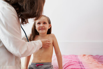 Pediatric doctor examine little happy girl with stethoscope. Chi