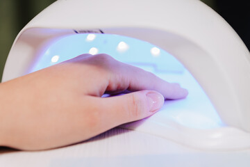 Manicure process. Drying nails in a device with ultraviolet lamps.