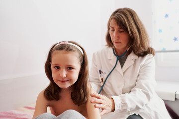 Pediatric doctor examine little happy girl with stethoscope. Chi