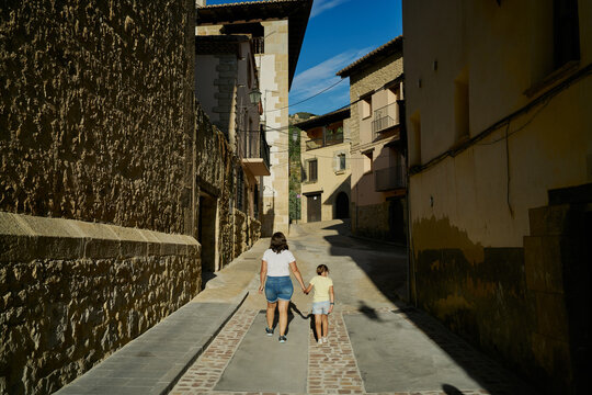 Mother and daughter walking in an alley with old houses in Mora