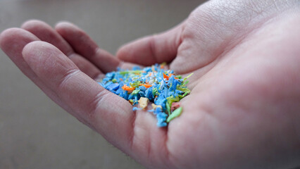 Side view of a person holding microplastics in his hand. Non-recyclable materials. Selective focus with shallow depth of field. Global warming and climate change concept.