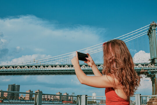 Young woman by river taking picture with phone