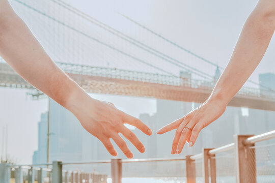 Two hands almsot touching against skyline.