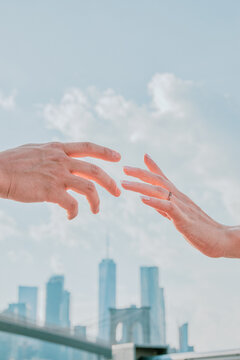 Two hands almsot touching against skyline.