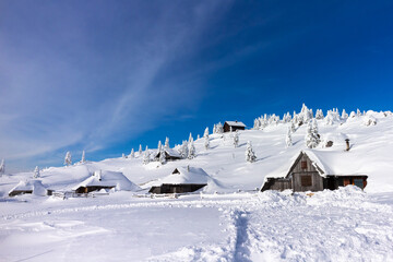 Winter landscape with snow covered shepherd's huts in mountains. Velika planina in Slovenia.