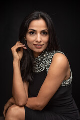 Studio images of beautiful Asian Indian woman wearing black dress on black background.