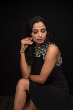 Studio images of beautiful Asian Indian woman wearing black dress on black background.