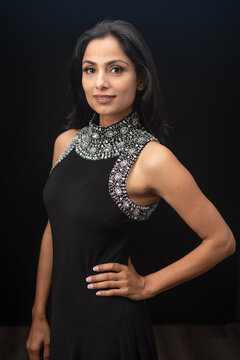 Studio images of beautiful Asian Indian woman wearing black dress on black background.