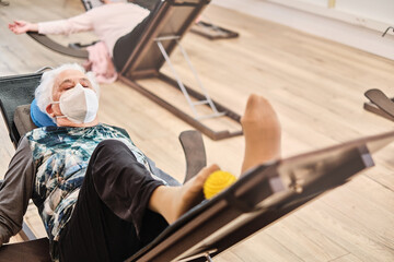 Old woman lying down doing a yoga exercise in a physiotherapy